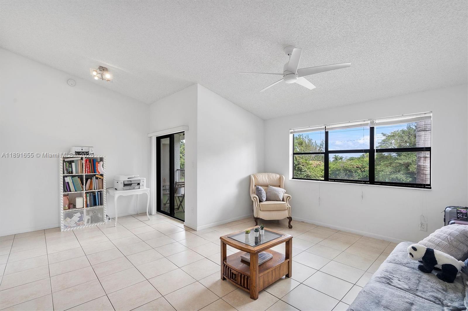 A bright living room features white walls, tile flooring, a ceiling fan, and large windows — 610 S Park Rd # 1, Hollywood FL 33021, HOLLYWOOD, FL
