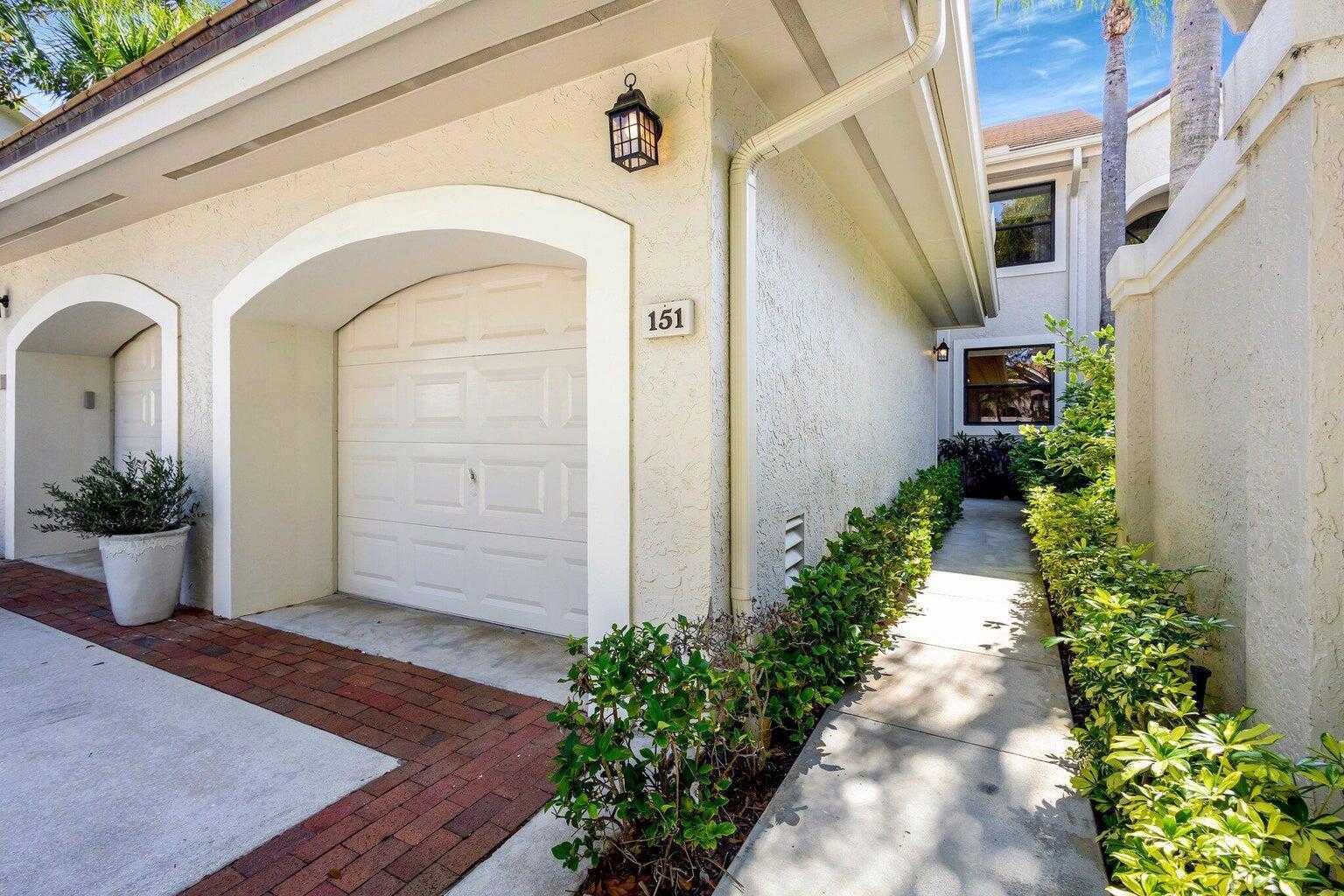 A white garage door with the number 151 is next to a concrete walkway — 16050 W Bay Drive # 151, Jupiter FL 33477, JUPITER, FL