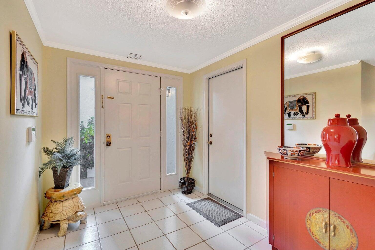 An entryway features white tile flooring, a front door with sidelights, and a red cabinet — 16050 W Bay Drive # 151, Jupiter FL 33477, JUPITER, FL