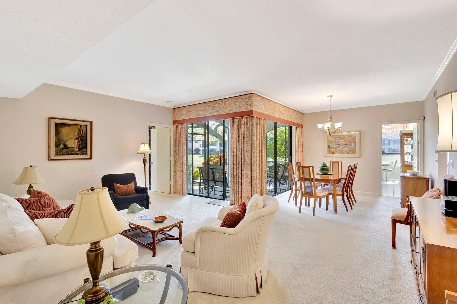 A living and dining area with beige carpeting, neutral walls, and sliding glass doors to a patio — 16050 W Bay Drive # 151, Jupiter FL 33477, JUPITER, FL