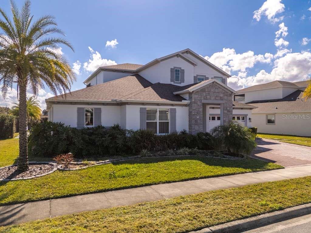 A two-story house with a stone-accented entryway, gray shutters, and a palm tree in front — 16870 SANCTUARY DRIVE, WINTER GARDEN, FL