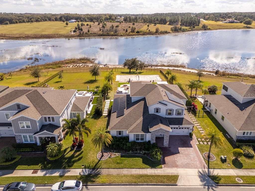 An aerial view of a suburban house with solar panels, a pool, and a lake — 16870 SANCTUARY DRIVE, WINTER GARDEN, FL