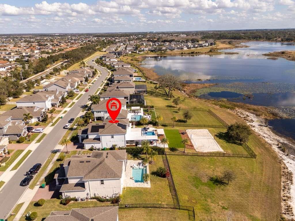 An aerial view shows a residential house with a pool next to a large lake — 16870 SANCTUARY DRIVE, WINTER GARDEN, FL
