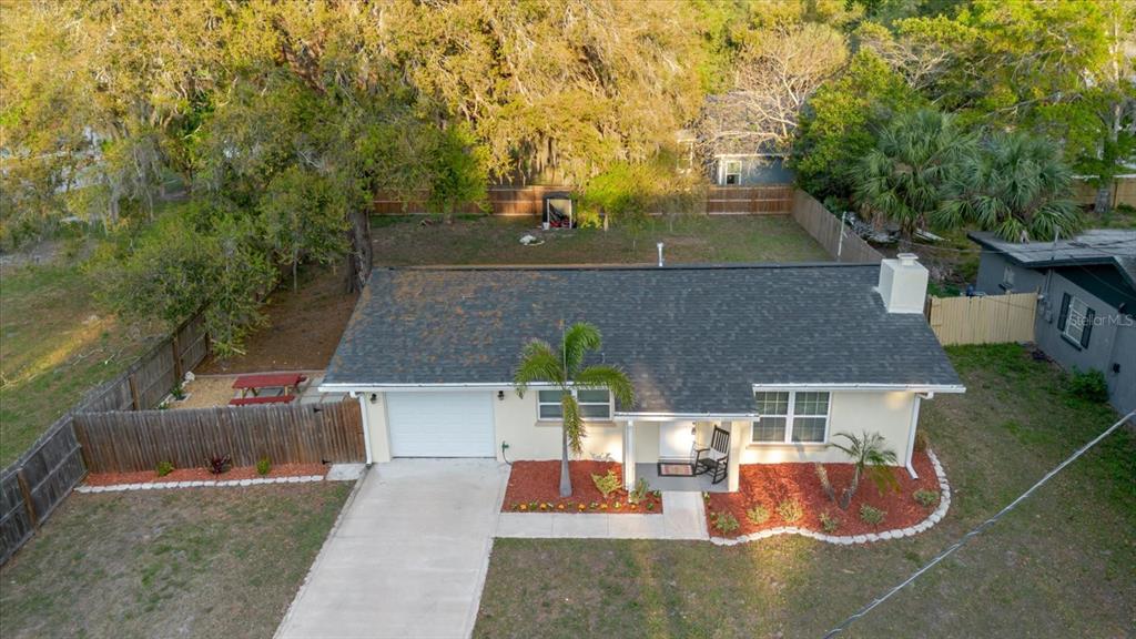 An aerial view of a single-story house with a shingled roof, garage, and fenced yard — 7800 WASHINGTON STREET, PORT RICHEY, FL