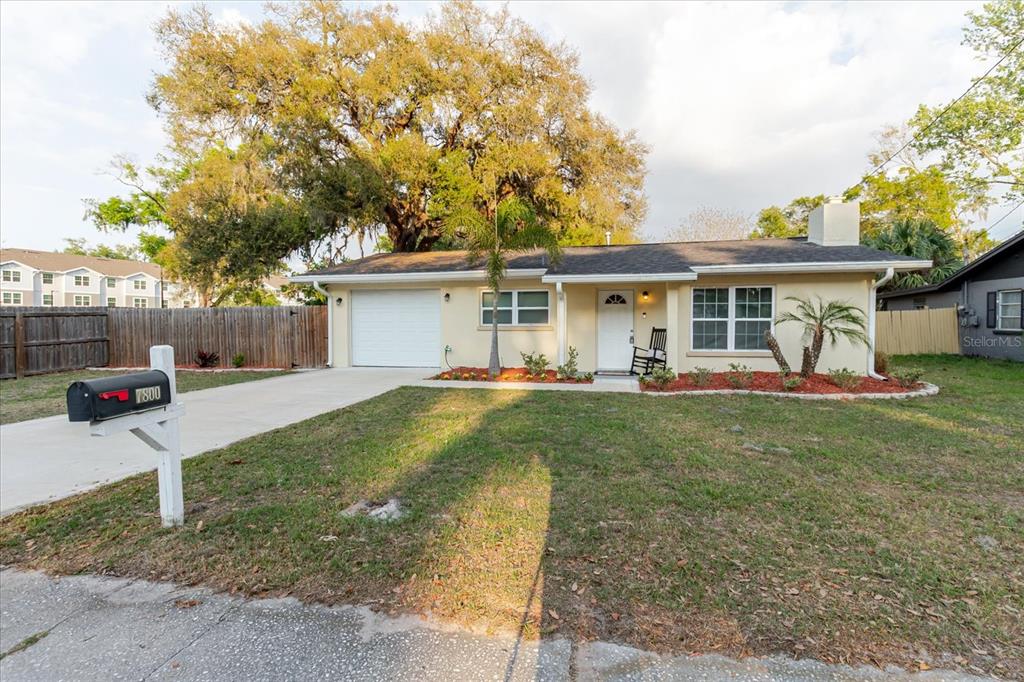 A single-story house with a white garage, beige siding, and a front lawn — 7800 WASHINGTON STREET, PORT RICHEY, FL
