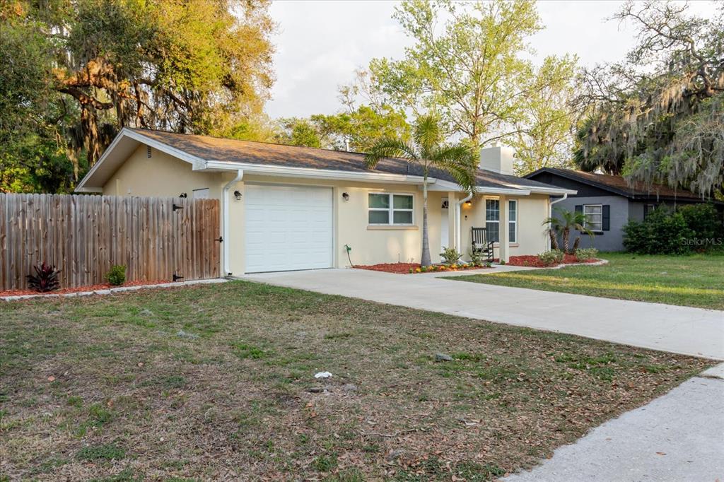 A single-story house with a white garage, beige siding, and a concrete driveway — 7800 WASHINGTON STREET, PORT RICHEY, FL