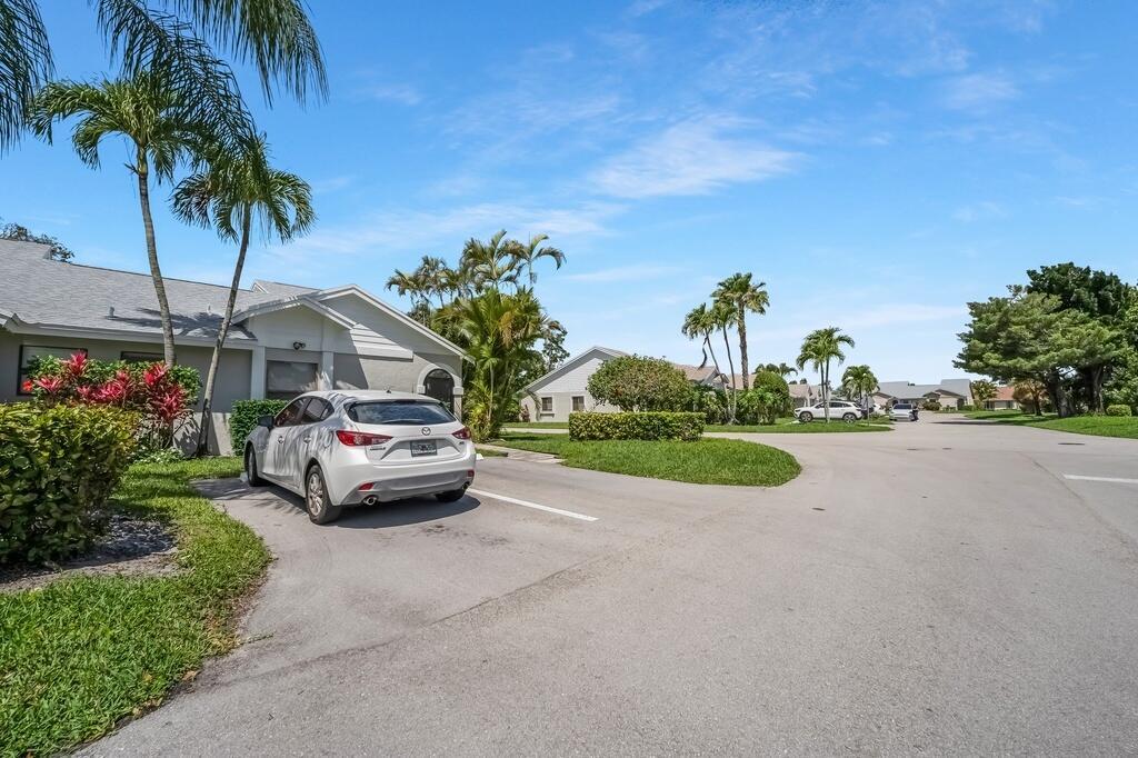 A white car is parked in the driveway of a suburban home with palm trees — 1260 NW 24th Avenue, Delray Beach FL 33445, DELRAY BEACH, FL
