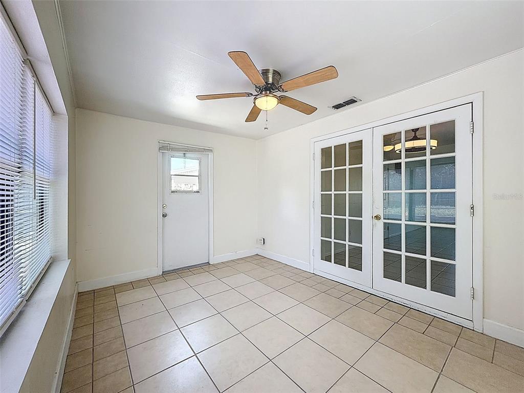 A sunroom features beige tile flooring, a ceiling fan, a white door, and French doors — 4130 CRESTFIELD AVENUE, HOLIDAY, FL