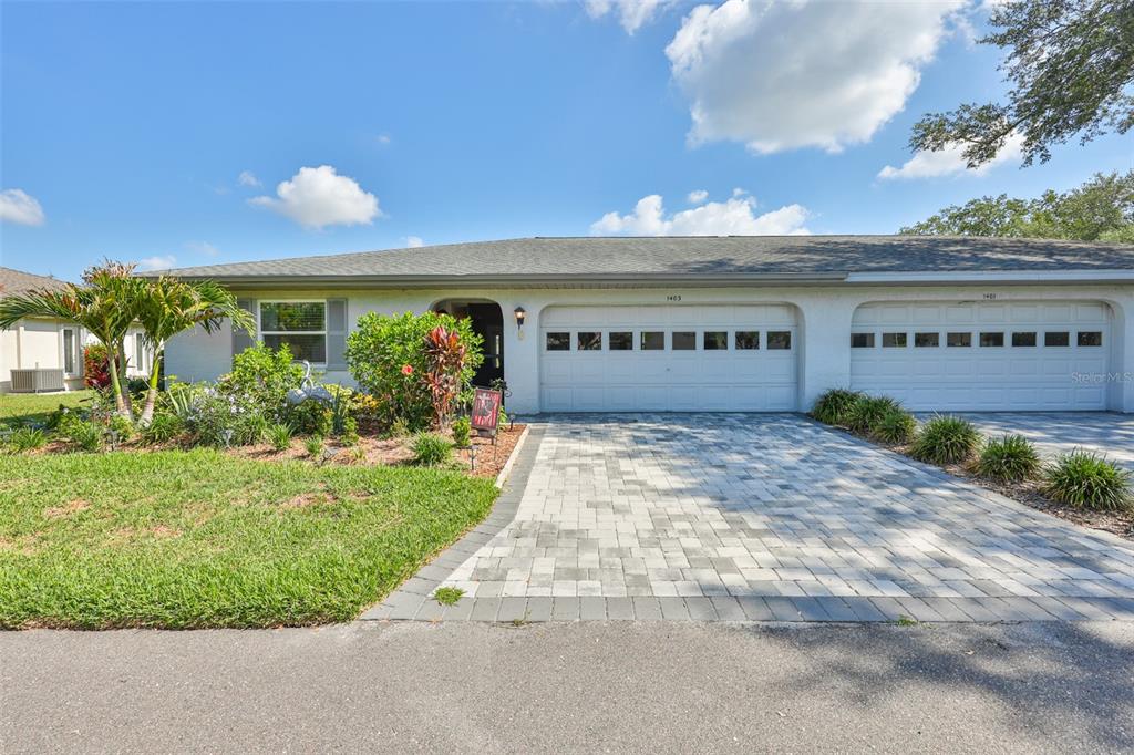 A single-story house with a white exterior, two garage doors, and a paved driveway — 1403 LANGLEY DRIVE, SUN CITY CENTER, FL
