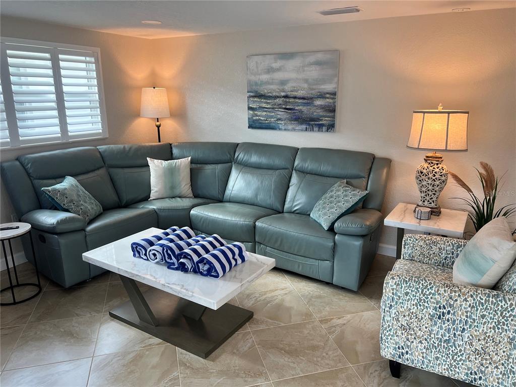 A living room features a blue sectional sofa, a marble coffee table, and patterned armchair — 6154 MIDNIGHT PASS ROAD UNIT A14, SARASOTA, FL