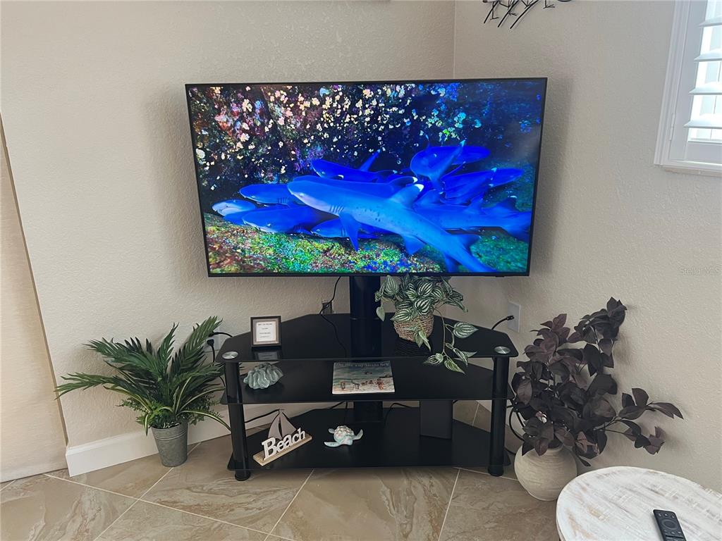 A television on a black stand sits in the corner of a room with tile flooring — 6154 MIDNIGHT PASS ROAD UNIT A14, SARASOTA, FL