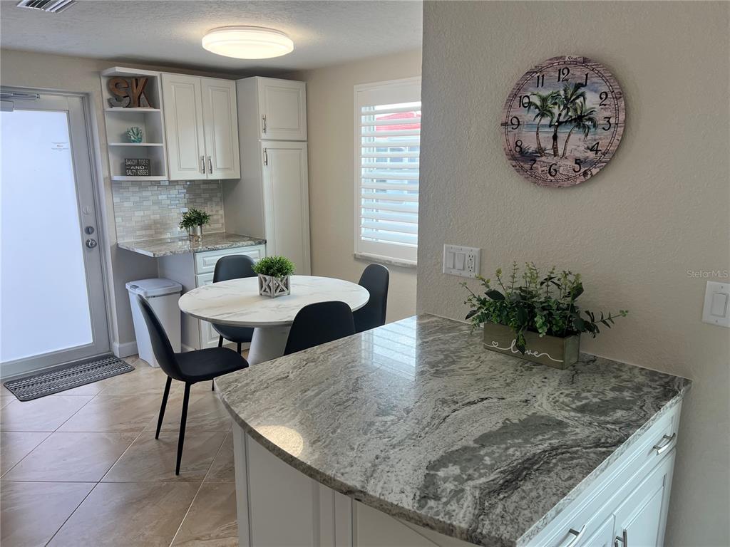 A kitchen and dining area feature white cabinets, granite countertops, and a round table — 6154 MIDNIGHT PASS ROAD UNIT A14, SARASOTA, FL