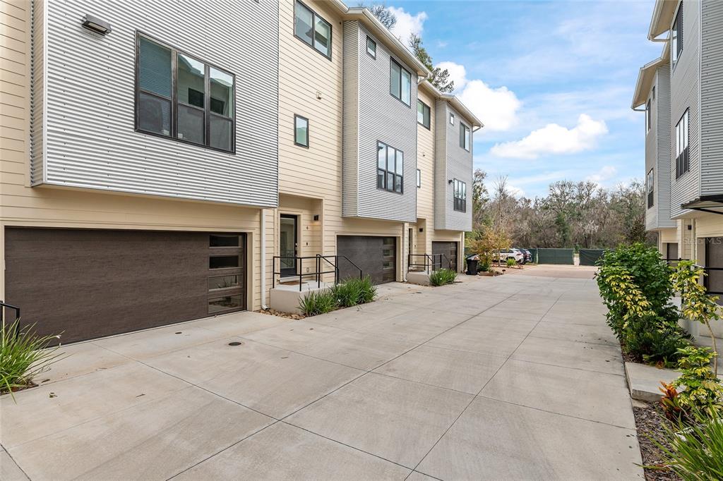 A row of modern townhomes with metal siding and attached garages faces a concrete driveway — 2601 SW WILLISTON ROAD UNIT 106, GAINESVILLE, FL