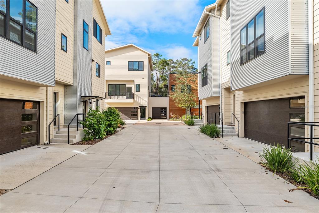 A paved driveway leads to the garages of several modern multi-story townhomes — 2601 SW WILLISTON ROAD UNIT 106, GAINESVILLE, FL