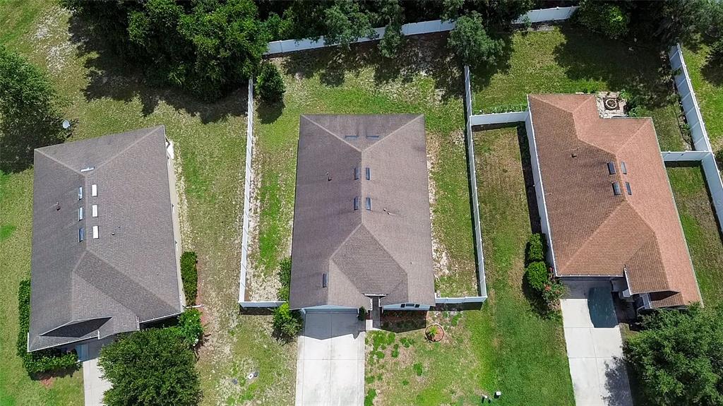 An aerial view shows three suburban houses with fenced backyards and concrete driveways — 665 CARYA COURT, DELAND, FL