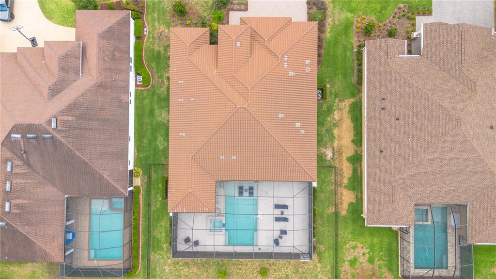 An aerial view shows three suburban houses with tiled roofs and screened-in swimming pools — 113 BROOKOVER LANE, BRANDON, FL