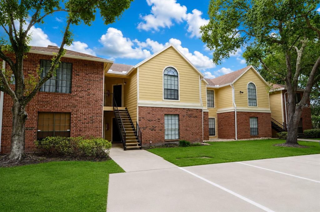 A two-story apartment building with brick and yellow siding features an exterior staircase — 8764 MALLARD RESERVE DRIVE UNIT 101, TAMPA, FL