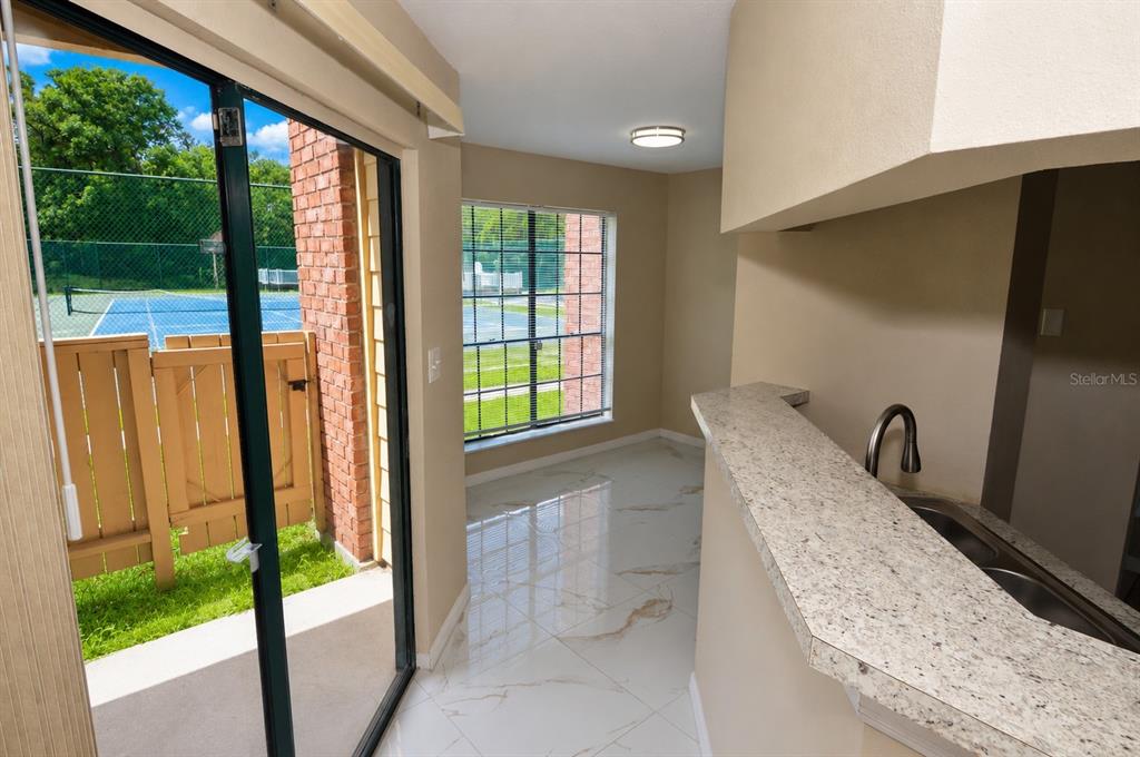 A kitchen with a granite breakfast bar overlooks a dining area with a sliding glass door — 8764 MALLARD RESERVE DRIVE UNIT 101, TAMPA, FL