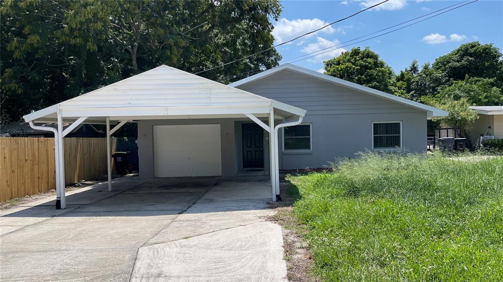 A single-story house with a white carport, gray exterior, and an overgrown front lawn — 253 W LAKE INA DRIVE, WINTER HAVEN, FL