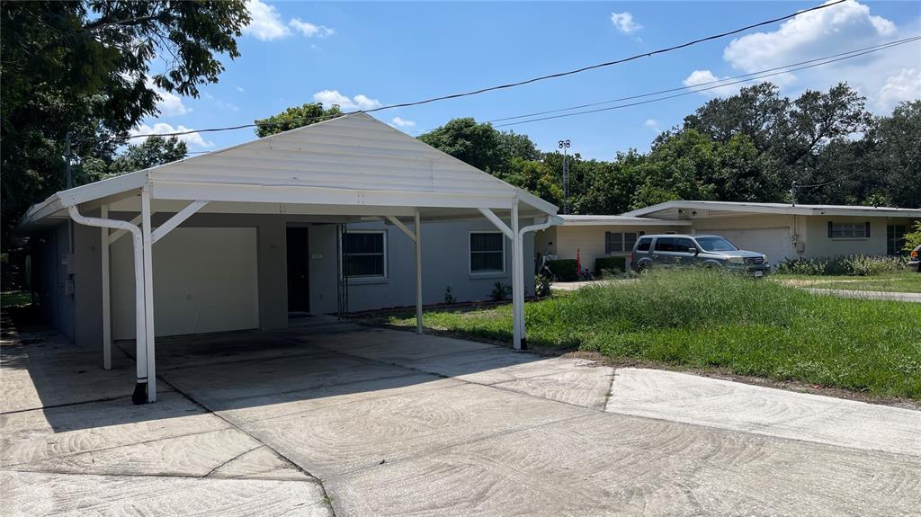 A single-story house with a white carport and a concrete driveway under a blue sky — 253 W LAKE INA DRIVE, WINTER HAVEN, FL