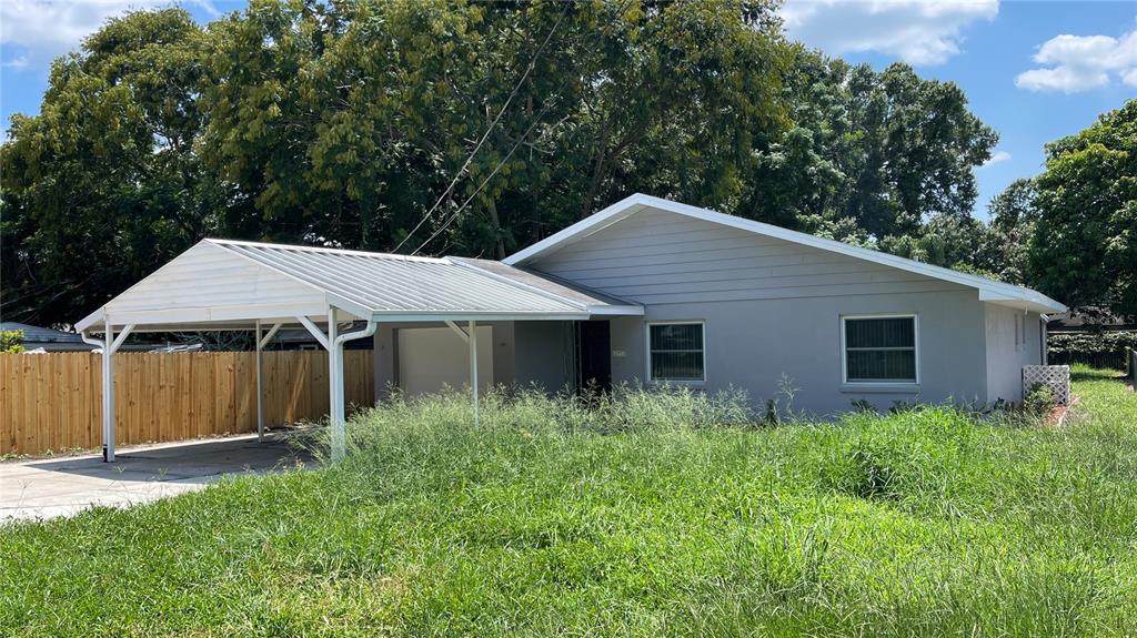 A single-story house with a metal carport and overgrown grass in the front yard — 253 W LAKE INA DRIVE, WINTER HAVEN, FL