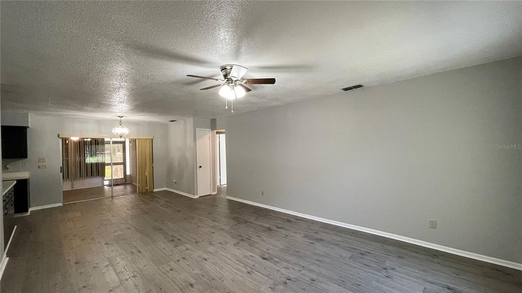 An open-concept living area features gray walls, wood-look flooring, and a ceiling fan — 253 W LAKE INA DRIVE, WINTER HAVEN, FL