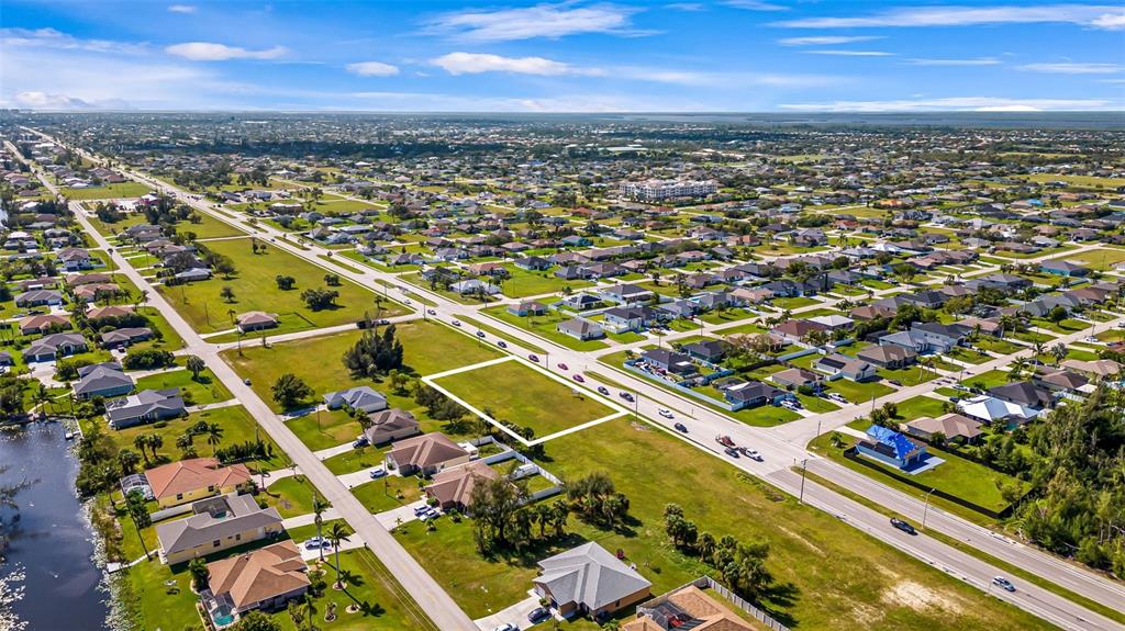 An aerial view shows a vacant rectangular residential lot situated between existing houses and roads — 1213 CHIQUITA BOULEVARD S, CAPE CORAL, FL