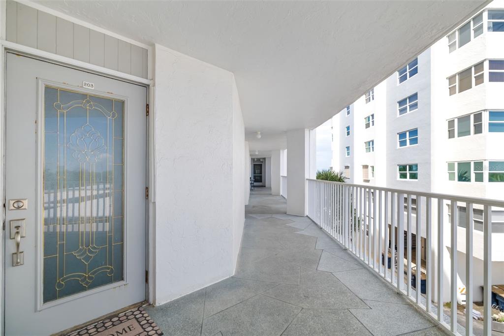 An exterior walkway leads to a front door with a decorative glass insert — 1770 BENJAMIN FRANKLIN DRIVE UNIT 203, SARASOTA, FL
