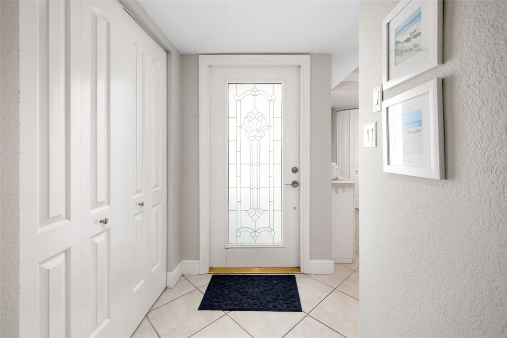 An entryway features a white front door with decorative glass, tile flooring, and closet doors — 1770 BENJAMIN FRANKLIN DRIVE UNIT 203, SARASOTA, FL