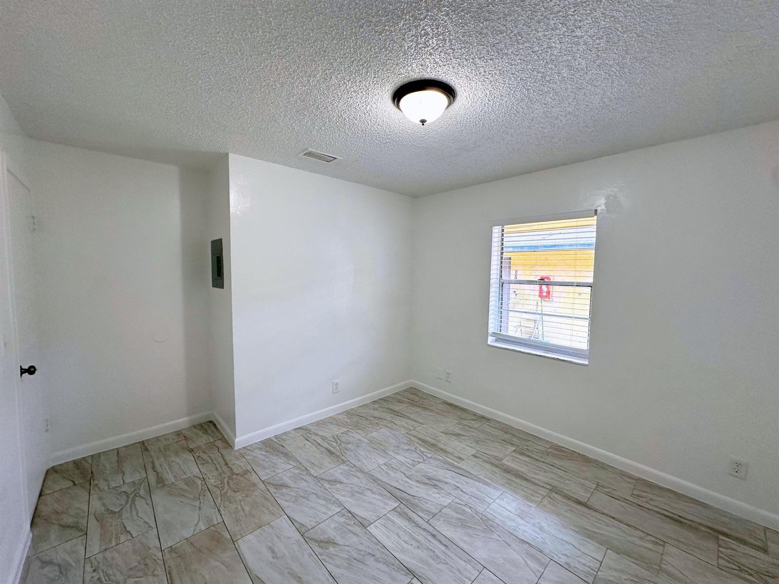 An empty room with white walls, light-colored tile flooring, a ceiling light, and a window — 329 Melody Lane, Lantana FL 33462, LANTANA, FL