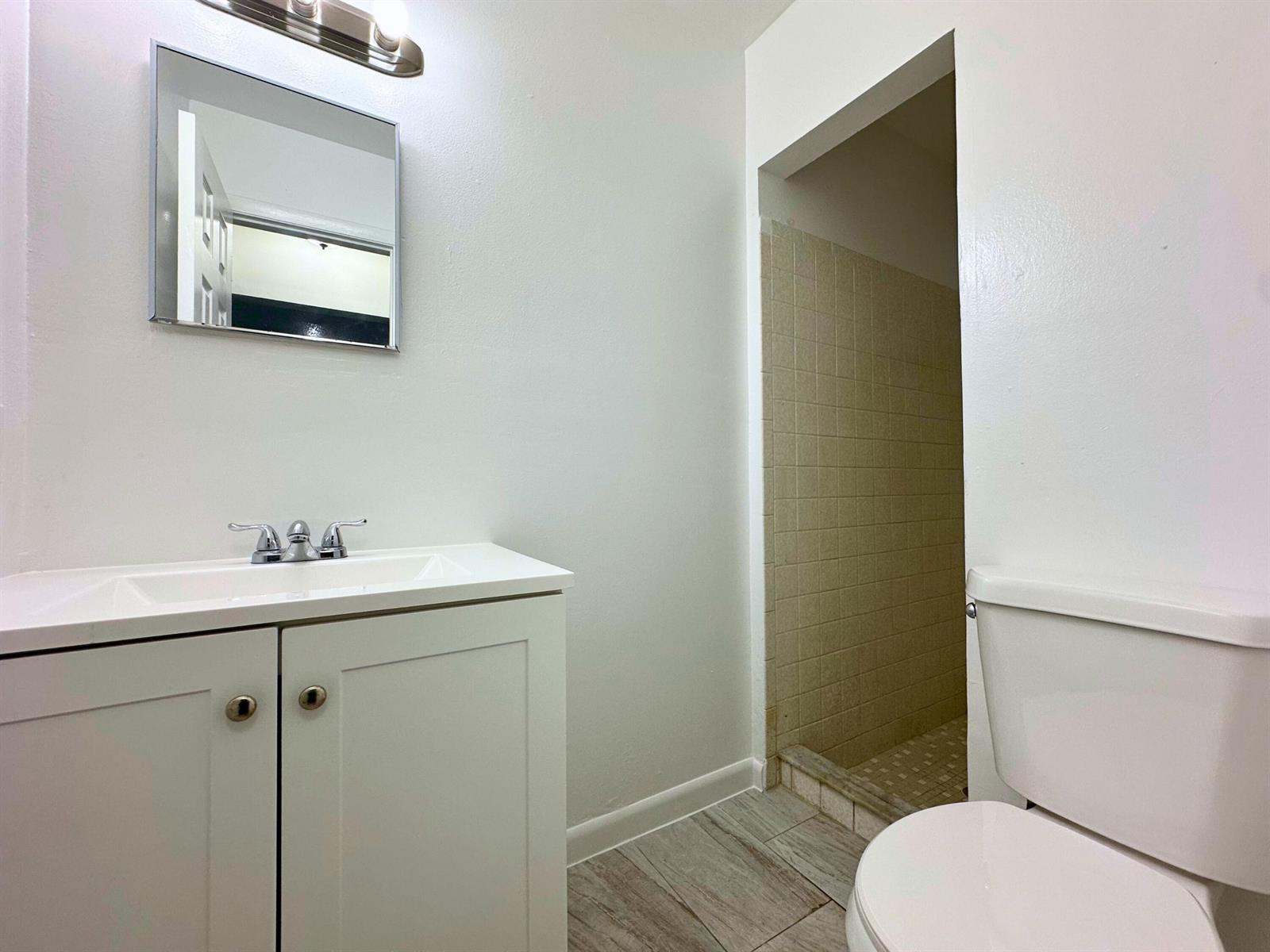 A bathroom features a white vanity, a mirror, a toilet, and a tiled shower stall — 329 Melody Lane, Lantana FL 33462, LANTANA, FL