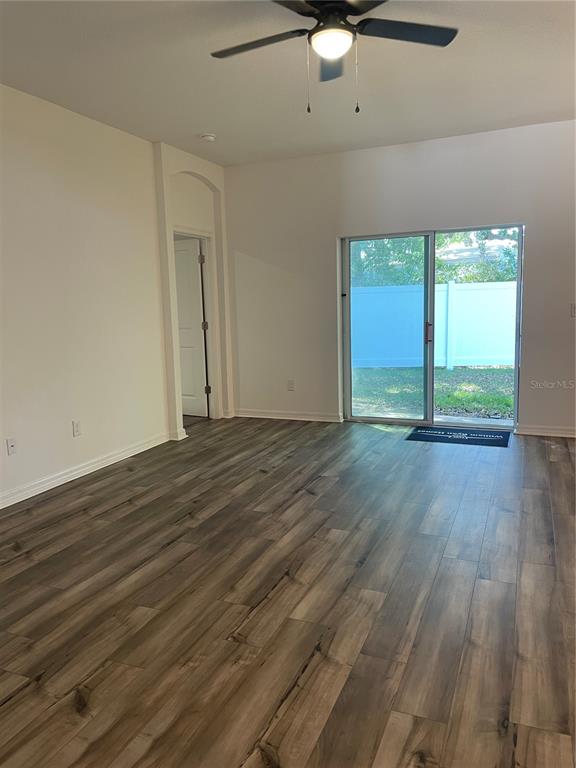An empty room with wood-look flooring, a ceiling fan, and a sliding glass door — 34772 MULRION DRIVE, ZEPHYRHILLS, FL