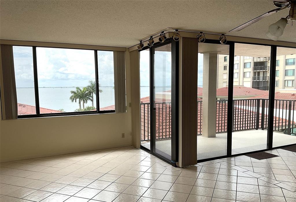 A tiled living room features large windows and sliding glass doors opening to a balcony — 6322 PALMA DEL MAR BOULEVARD S UNIT G402, ST PETERSBURG, FL