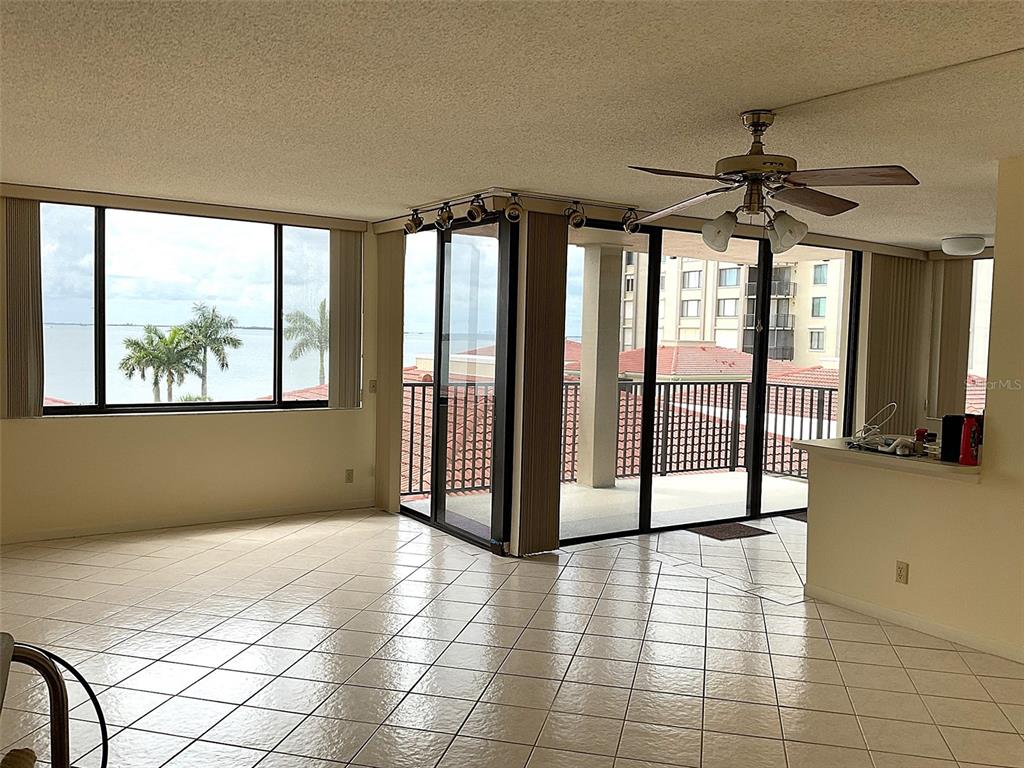 A tiled living area features a ceiling fan, sliding glass doors, and views of water — 6322 PALMA DEL MAR BOULEVARD S UNIT G402, ST PETERSBURG, FL
