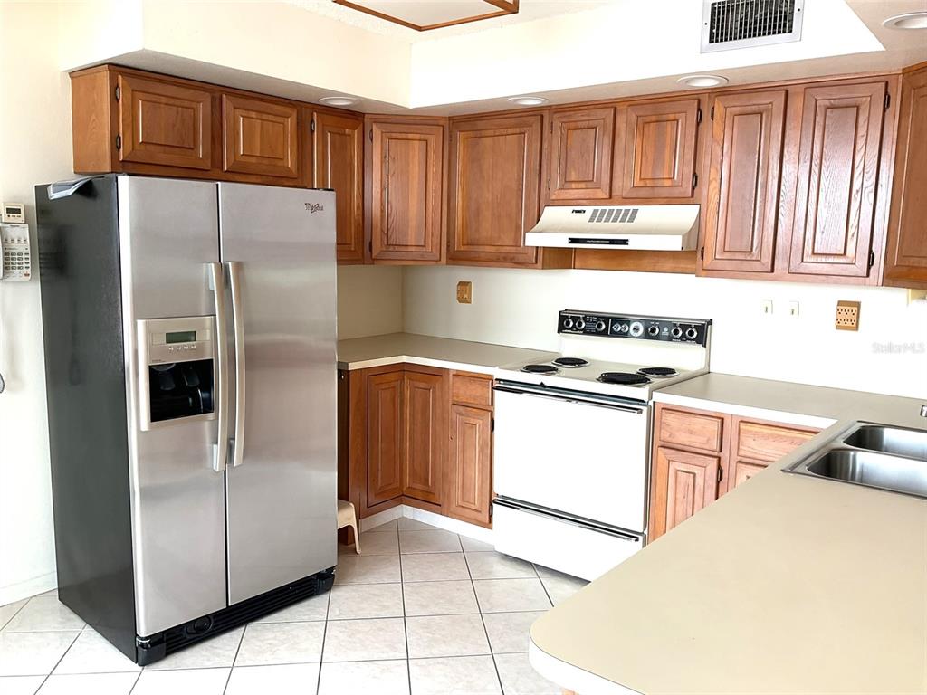 A kitchen features wood cabinets, stainless steel refrigerator, white stove, and light-colored countertops — 6322 PALMA DEL MAR BOULEVARD S UNIT G402, ST PETERSBURG, FL