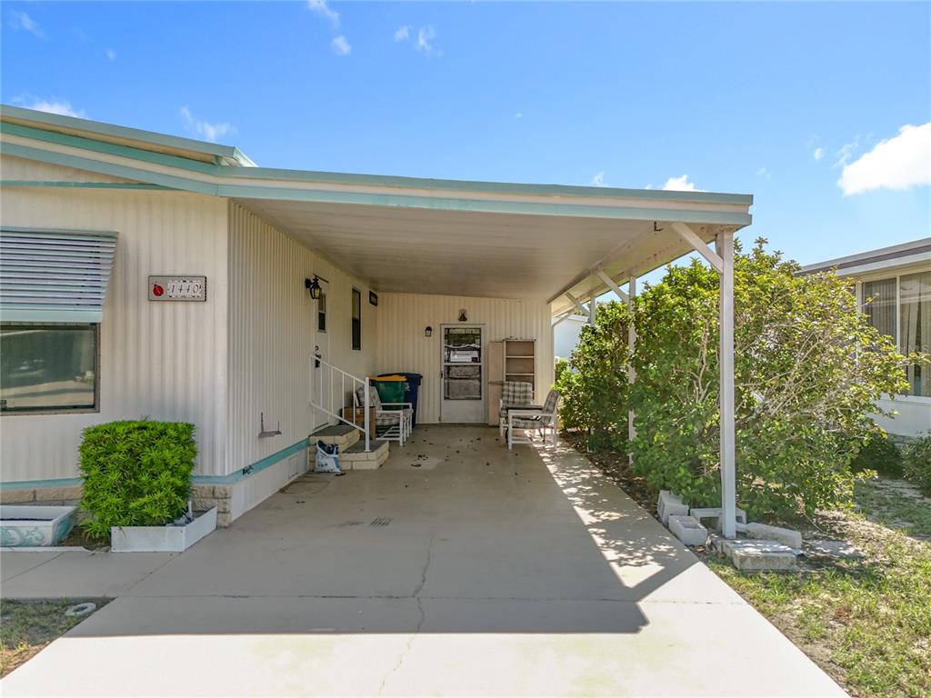 A mobile home exterior features a concrete driveway, a covered carport, and a side entrance — 1440 NASSAU CIRCLE, TAVARES, FL