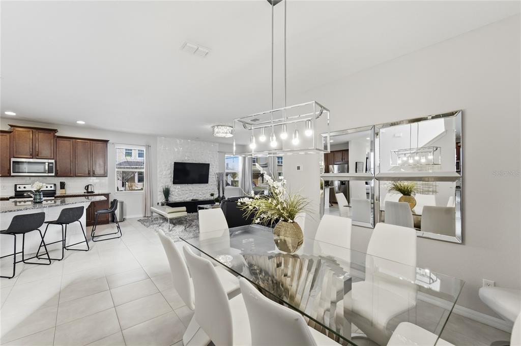A dining area with a glass table and chairs opens to a kitchen and living room — 9013 EGRET MILLS TERRACE, KISSIMMEE, FL