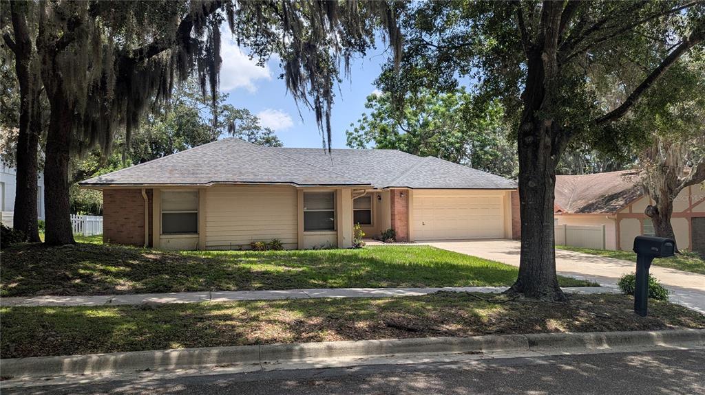A single-story house with beige siding, a brick facade, and a two-car garage — 8067 SWEETGUM LOOP, ORLANDO, FL