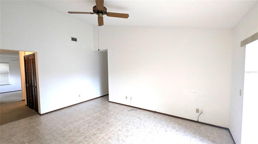 An empty room with white walls, a ceiling fan, and light-colored tile flooring — 8067 SWEETGUM LOOP, ORLANDO, FL