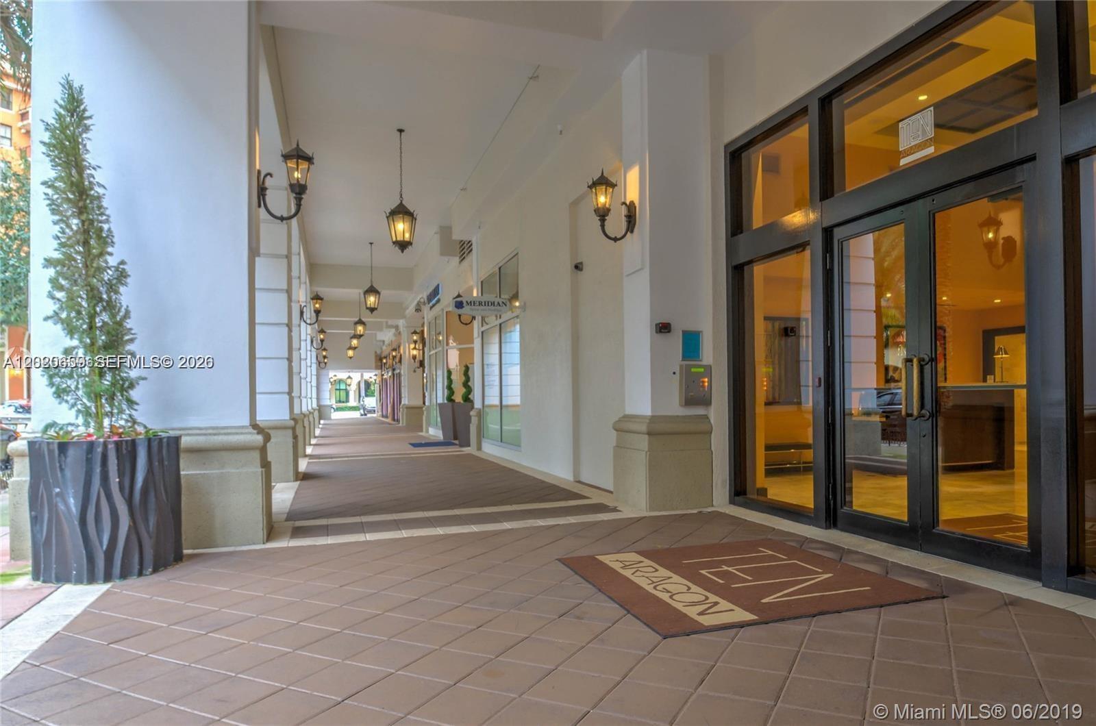 A covered outdoor walkway leads to the glass-paned entrance of a building — 10 Aragon Ave # 1018, Coral Gables FL 33134, CORAL GABLES, FL