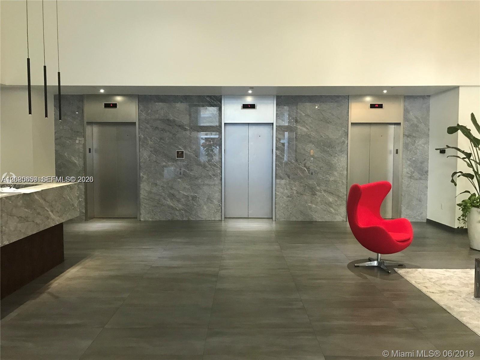A modern lobby features three stainless steel elevators set against gray marble walls — 10 Aragon Ave # 1018, Coral Gables FL 33134, CORAL GABLES, FL