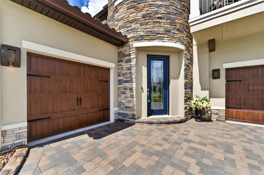 A stone-clad turret entrance sits between two wooden garage doors on a paved driveway — 4285 STAR VIEW PLACE, BRANDON, FL