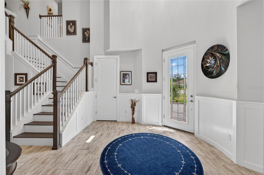 A bright foyer features a staircase with wooden railings, a blue rug, and a front door — 4285 STAR VIEW PLACE, BRANDON, FL