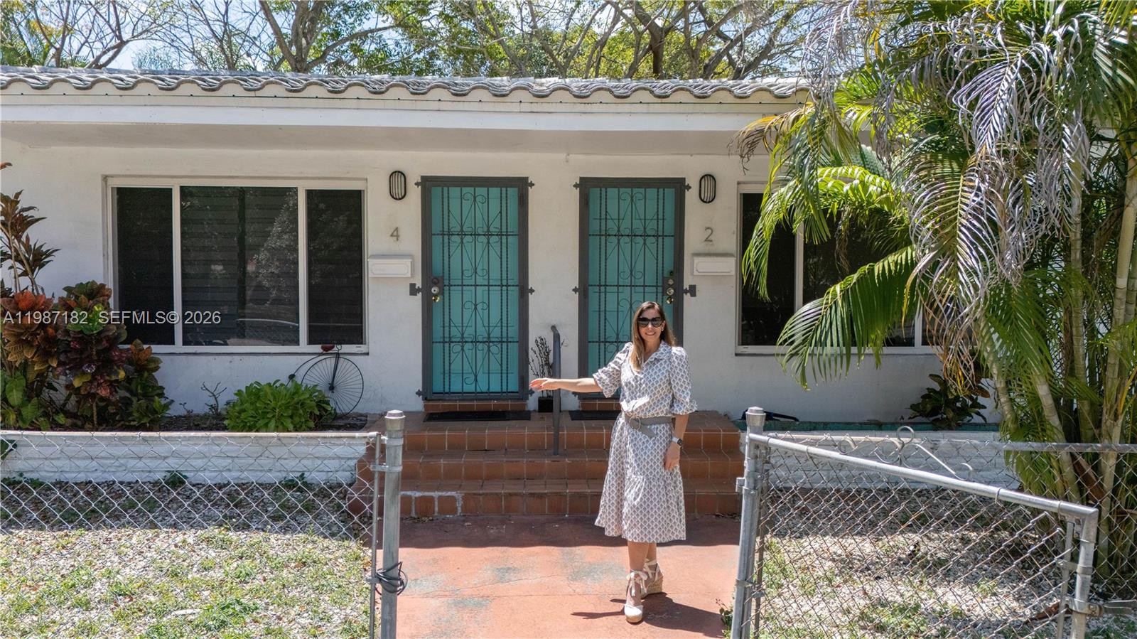 A woman stands in front of a white duplex with two turquoise screen doors — 2 NE 45th St, Miami FL 33137, MIAMI, FL