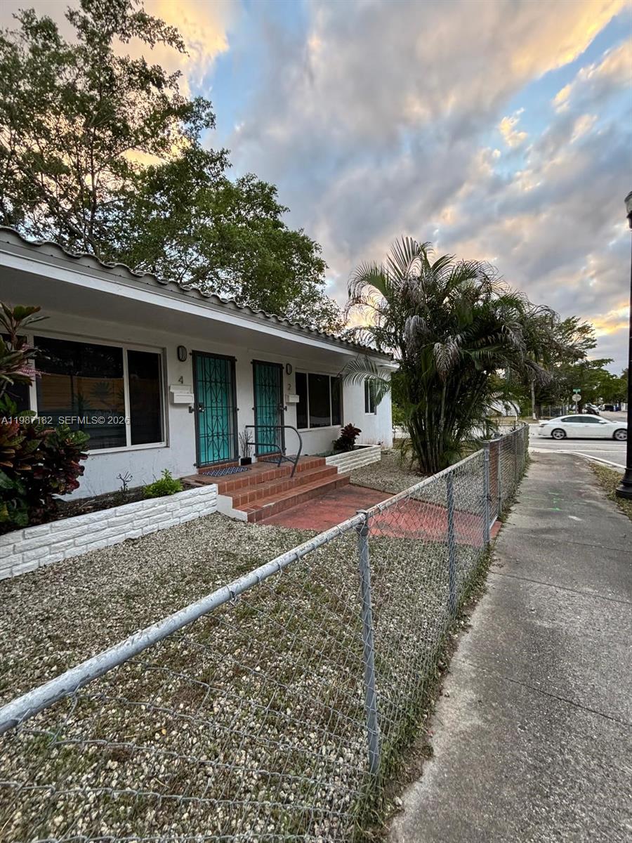 A single-story duplex with white walls, turquoise security doors, and a chain-link fence — 2 NE 45th St, Miami FL 33137, MIAMI, FL