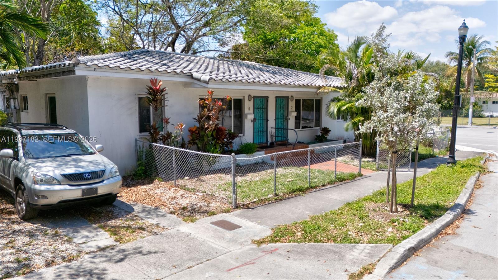 A single-story white house with a tiled roof and a chain-link fenced front yard — 2 NE 45th St, Miami FL 33137, MIAMI, FL