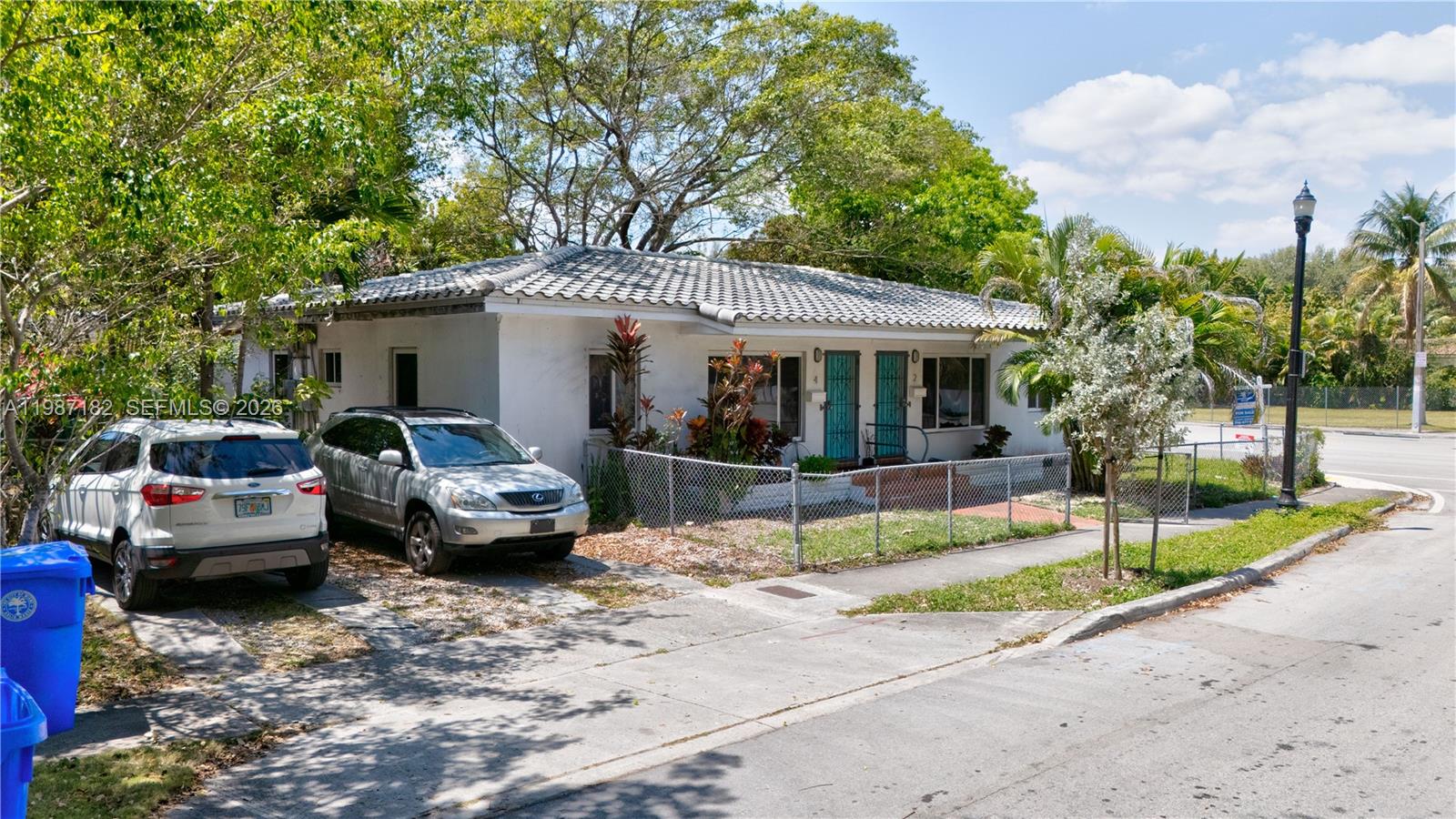 A single-story white house with a tiled roof sits behind a chain-link fence — 2 NE 45th St, Miami FL 33137, MIAMI, FL