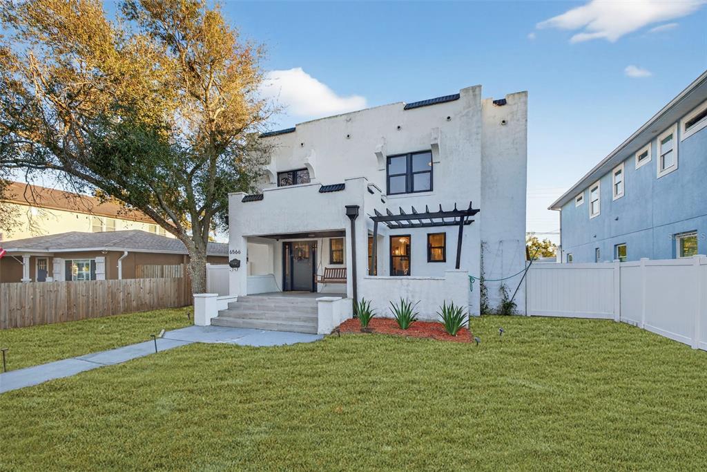 A white two-story house with a front porch, pergola, and a grassy front yard — 6566 1ST AVENUE S, ST PETERSBURG, FL