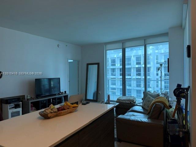 A modern living room features a kitchen island, a television, and a sofa near windows — 1100 S Miami Ave # 801, Miami FL 33130, MIAMI, FL