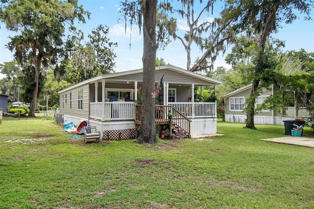 A mobile home features a raised wooden deck with stairs and a white railing — 123 MAGNOLIA DRIVE, SATSUMA, FL